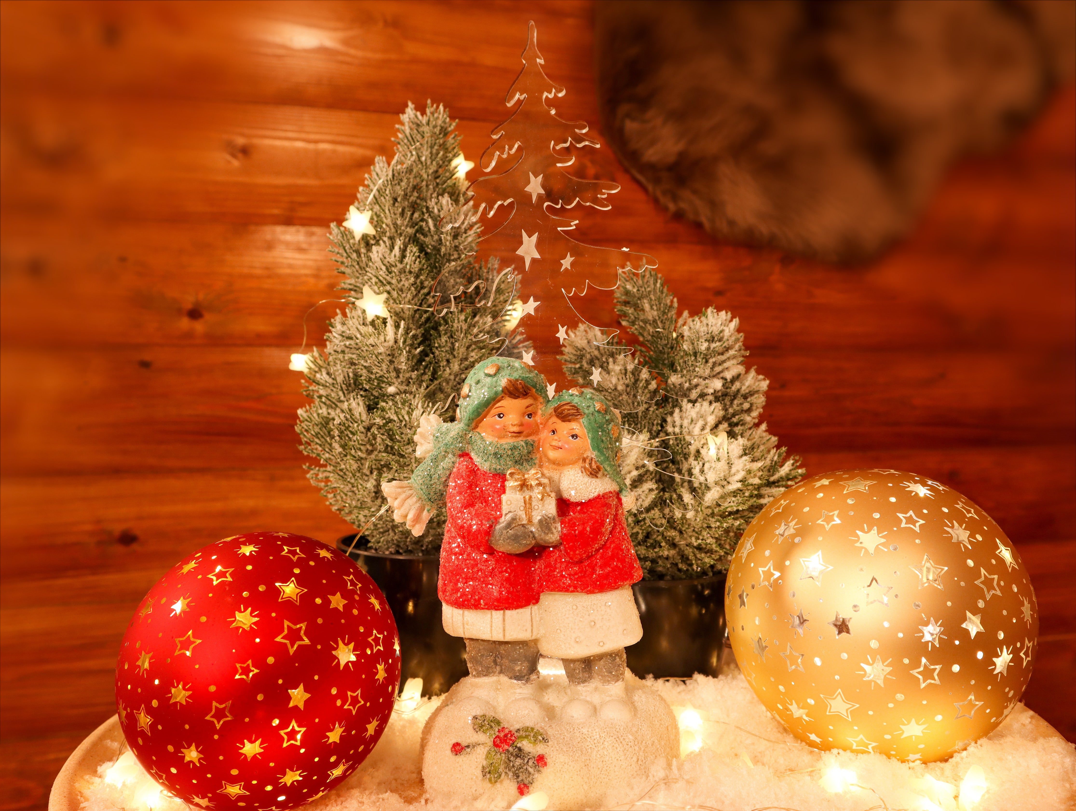 Kinderpaar mit Geschenk vor Acryl Tannenbaum